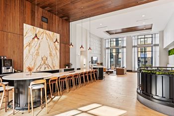 A modern kitchen with a long bar and wooden floors.